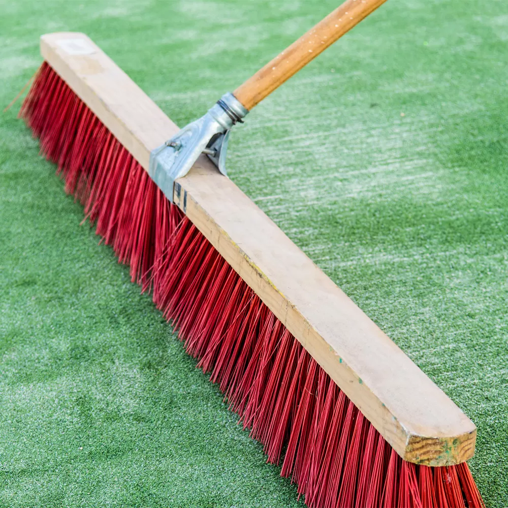 grooming artificial grass turf with large broom