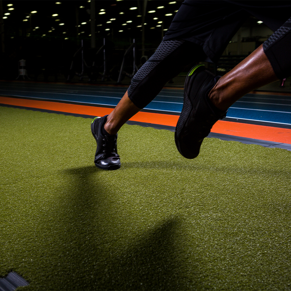 athlete running on green turf tiles