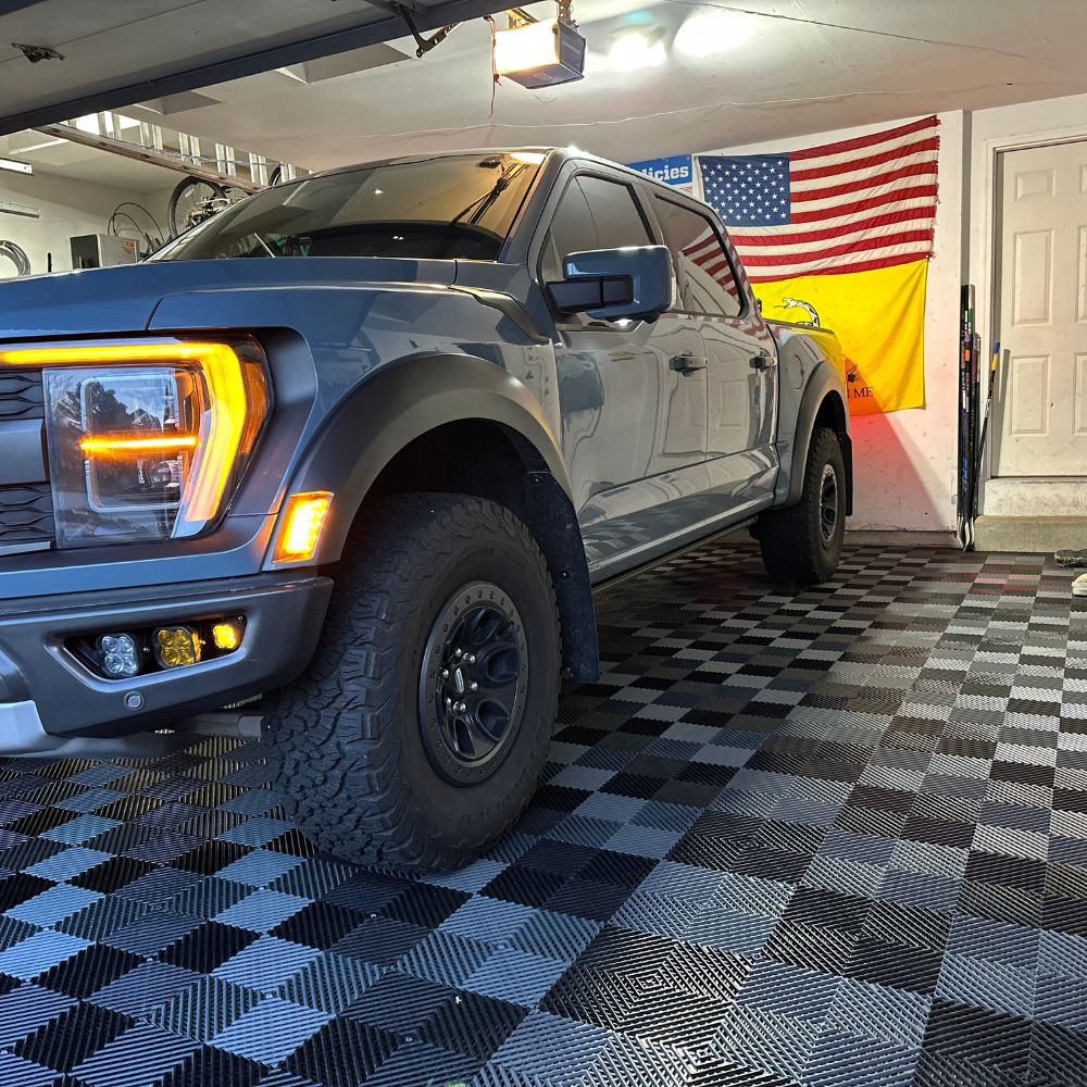 garage with truck showing black and gray raised interlocking tiles for flooring