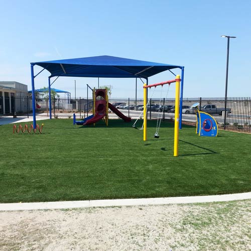 playground with artificial turf under shade structure