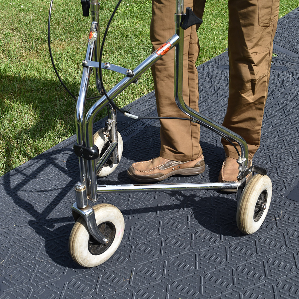 portable makeshift sidewalk with outdoor mats over grass man with walker