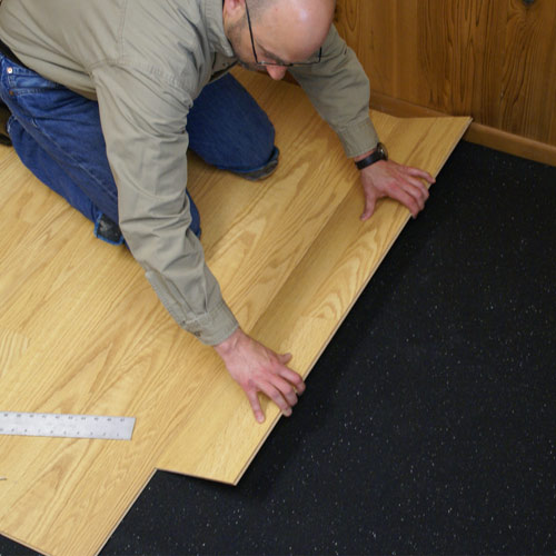 man installing laminate flooring over silenttread rubber underlayment