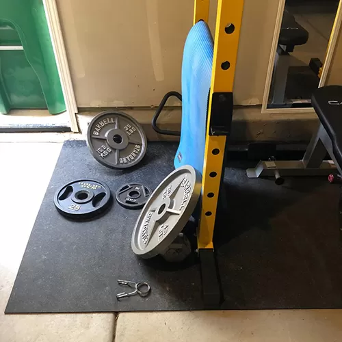 garage gym set up with equipment and rubber floor mats